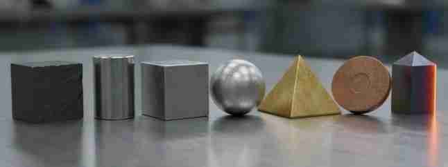 Campioni di diversi materiali metallici accostati a elementi che richiamano i trattamenti termici, su superficie industriale.